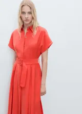 Vestido midi camisero color coral, de corte evasé, manga corta, cuello camisero, cierre frontal con botones y cinturón con hebilla.