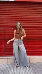 Pantalón de jean celeste de tiro medio con pierna extra ancha y caída fluida, con bolsillos delanteros y traseros, y cierre frontal con cremallera y botón metálico.