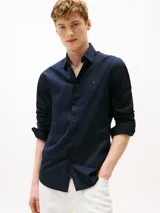 Camisa de manga larga Tommy Hilfiger color azul marino, de corte regular, confeccionada en popelina elástica de algodón regenerativo, algodón BCI y elastano. Presenta cuello clásico, cierre con botones, puños abotonados y logo bordado en el pecho.