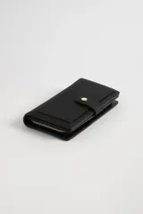 Billetera negra con textura, cierre con broche dorado y compartimento con cierre de cremallera.