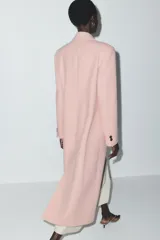 Abrigo largo color rosa pálido, de corte recto, con cuello solapa, cierre frontal con un botón y bolsillos laterales de ojal.