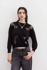 Sweater negro de punto con cuello redondo y mangas largas. Presenta recortes de encaje en la parte superior delantera y en los hombros.