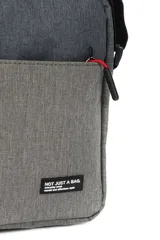 Bandolera negra rectangular de poliéster con correa ajustable y cierre superior. Tiene un bolsillo frontal con cierre y tiradores de cierre rojos.