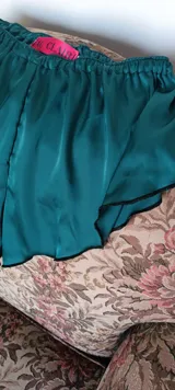 Mini culotte color verde esmeralda confeccionado en satén dull, con cintura elástica y terminaciones con puntilla negra.