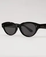 Anteojos de sol negros con montura de acetato premium y forma de ojo de gato. Los cristales son oscuros y polarizados con filtro UV 400. Presentan pequeños remaches decorativos en la parte frontal superior y un logo grabado en la patilla derecha.