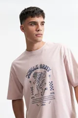 Remera color rosa claro de corte oversize y mangas cortas. Estampado frontal con la leyenda "Jungle Army", un tigre y otros símbolos.