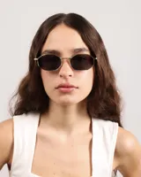 Lentes de sol con marco dorado y forma ovalada.