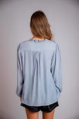 Camisa celeste con volados en cuello y en la parte delantera, con cordones.