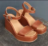 Sandalias de cuero color marrón con plataforma y taco ancho. Tiras anchas sobre el empeine y tobillo con hebilla metálica.