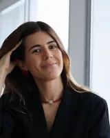 Gargantilla de cuentas rojas con dije central de nácar blanco en forma de pez.
