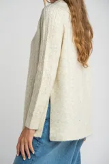 Sweater color beige de tejido texturado, con cuello redondo y mangas largas.