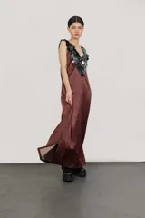 Vestido largo de seda color bordó, con escote en V y apliques de lentejuelas iridiscentes en el cuello y los hombros.