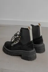 Borcego de gamuza color verde militar con elásticos laterales negros, cordones negros y suela de goma negra con plataforma.