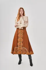 Falda midi marrón con estampado floral y lunares blancos, corte acampanado y cintura alta.