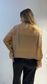 Camisa negra de gasa con escote en V, doble volado frontal, mangas largas abullonadas con puños elásticos y cierre frontal con botones.