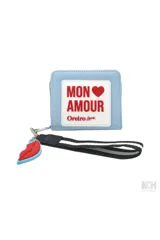 Billetera tipo monedero de color celeste claro, con cierre de cremallera y detalle frontal con texto 'MON AMOUR' en un parche blanco. Incluye un llavero desmontable con forma de labios rojos y una correa de mano negra con franjas blancas.