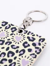 Llavero porta tarjeta rectangular con estampado animal print en tonos beige y negro, con corazones lilas.