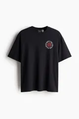 Remera negra de algodón con estampado del logo de la banda Red Hot Chili Peppers en el pecho. Corte holgado y cuello redondo.