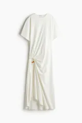 Vestido tobillero de punto de algodón suave color blanco, de corte holgado con cuello redondo, mangas dolman hasta el codo y tajo largo delantero con argolla metálica y cuenta decorativa para efecto drapeado.