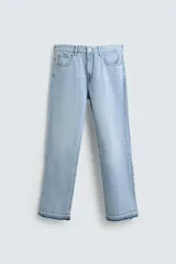Pantalón de jean celeste de corte flare, con tiro medio, cinco bolsillos, cierre frontal con cremallera y botón, y bajo con acabado irregular.