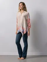 Blusa de gasa color beige con estampado floral en tonos rosa y celeste. Tiene cuello a la base, escote en V y abertura central con botones. Las mangas son 3/4 y regulables con presilla y botón.