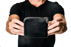 Billetera negra de cuero con cierre perimetral, compartimentos internos para tarjetas, billetes y monedas.