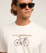 Remera color crudo de algodón, de cuello redondo y manga corta. Presenta un estampado con una bicicleta de carreras y la palabra "Racing".