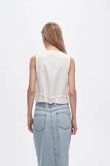 Chaleco blanco sin mangas con cuello en V y cierre frontal con botones.