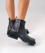 Botas Chelsea de cuero vacuno negro con elásticos laterales, cierre interno y suela de goma artesanal.