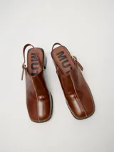 Zuecos clásicos color beige, hechos 100% en cuero vacuno wax y charol, con taco de madera de 5cm de altura y correa trasera ajustable.