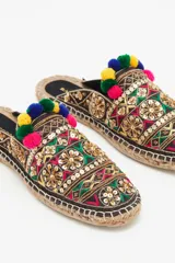 Zueco abierto con bordados, lentejuelas, canutillos y pompones de colores. Suela de yute y taco de madera de 1,5 cm.