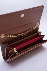 Cartera tipo sobre color beige con textura granulada y correa de cadena dorada.