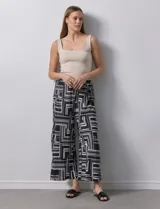 Pantalón ancho estilo palazzo, de seda fría plisada con estampado geométrico en negro, blanco y beige. Tiene pretina ancha elastizada y largo crop.