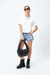 Short de jean celeste con roturas, ruedo desflecado y tachas plateadas.