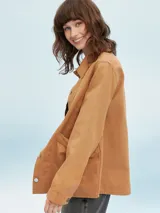 Sobrecamisa color beige, de corte recto, con cuello camisero, cierre frontal con botones a presión, mangas largas con puños abotonados, dos bolsillos de parche en el pecho y bajo recto.