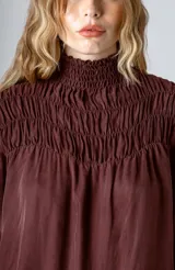 Blusa negra con cuello alto fruncido y mangas largas abullonadas con puños elásticos.