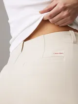 Pantalón de vestir color beige, de corte recto y tiro alto, confeccionado en crepé elástico. Presenta cintura plisada, bragueta con cremallera y cierre oculto, bolsillos laterales y traseros de ojal.