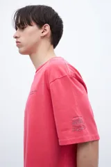 Remera roja de algodón con calce oversize, teñida en prenda con arte en el pecho y bordado en la manga.