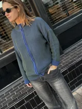 Campera tejida color gris con textura vanizada, cierre frontal con cremallera azul y cuello alto.