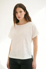 Blusa blanca con estampado de hojas en relieve, cuello redondo y mangas cortas.