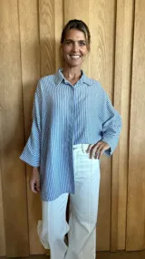 Camisa celeste y blanca a rayas verticales, de corte holgado y manga larga.