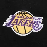 Pantalón de jogging negro con puños elásticos y cordón ajustable en la cintura. Presenta el logo de Los Angeles Lakers en la pierna derecha y el escudo del equipo en la pierna izquierda.