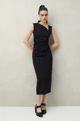 Vestido midi negro de punto, con cuello asimétrico y frunces laterales.