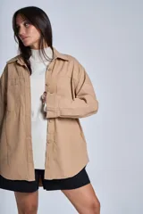 Sobrecamisa negra de gabardina con cuello camisero, cierre frontal con botones, mangas largas con puños abotonados y bolsillos de parche en el pecho.