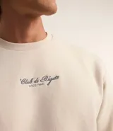Buzo color crema de algodón y poliéster con cuello redondo, mangas largas y estampa bordada con letras en el pecho.