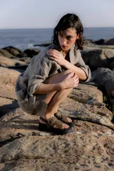 Sandalias bajas color marrón de cuero gamuzado, con tiras cruzadas y hebilla metálica.