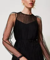 Vestido largo de tul negro con volantes plisados e inserciones de encaje. Presenta un escote redondo con lágrima, manga larga transparente, cremallera invisible lateral, cinturón fino de la misma tela y combinación, de corte ancho.