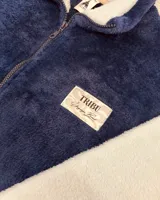 Campera de peluche azul con mangas blancas, cierre frontal y cuello alto.