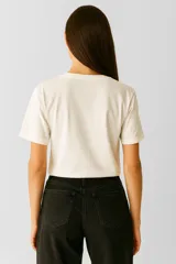 Remera color crema de algodón con cuello redondo y mangas cortas. Estampado frontal con dibujo de langosta y ostras sobre fondo de rayas verticales color naranja.