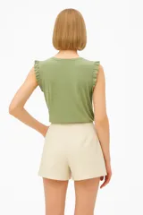 Musculosa color rosa pálido sin mangas, con cuello redondo y detalle de broderie con volados en el canesú.